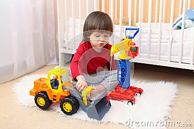 Lovely 2 years toddler boy plays cars at home Stock Photo