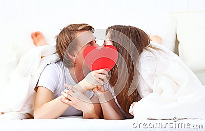 Lover couple kissing with a red heart in bed Stock Photo