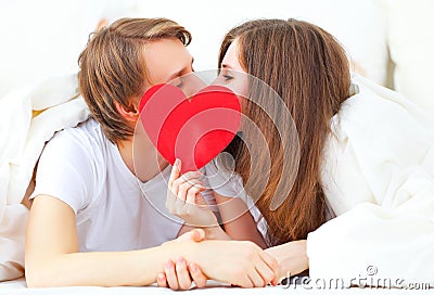Lover couple kissing with a red heart in bed Stock Photo