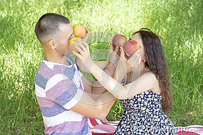 Lovers boy and girl dabble apples close each others eyes. emotions. summer picnic Stock Photo