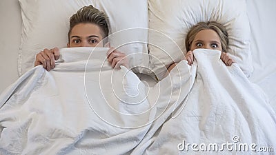 Lovers caught in bed by parents, embarrassed and frightened, looking shocked Stock Photo