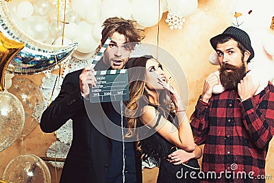 Lovers celebrate christmas or new year, love triangle. Boyfriends with movie clapper and teddy bear toy. Sensual woman Stock Photo