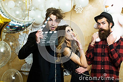 Lovers celebrate christmas or new year, love triangle. Boyfriends with movie clapper and teddy bear toy. Sensual woman Stock Photo