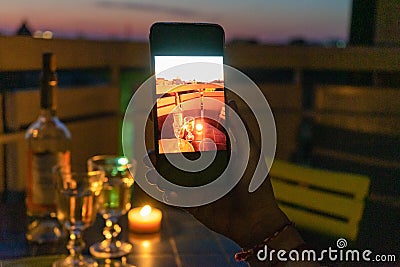 Lovers celebrate romantic dinner on the terrace with the light of the candle and wine on the confined of the quarantine. Stock Photo