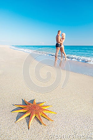 Lovers couple at sandy sea beach with big red starfish Stock Photo