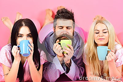 Lovers in love drink coffee in bed. Threesome relax in morning with coffee. Lovers concept. Man and women in domestic Stock Photo