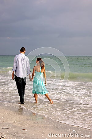 Lovers walking hand in hand along the beach in flo Stock Photo