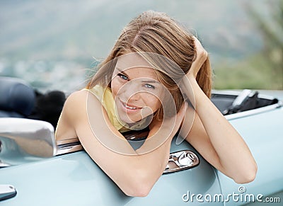 She loves to get on the road. A gorgeous young woman relaxing in a convertible while on a roadtrip. Stock Photo