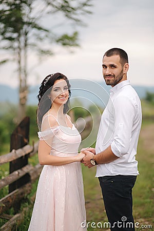 Lovestory of beautiful couple in the mountains, Handsome bearded man with beautiful and charming woman. Couple stand in Stock Photo