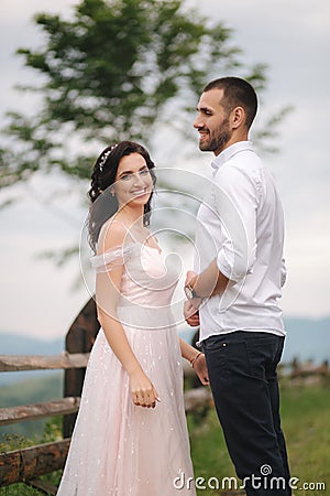 Lovestory of beautiful couple in the mountains, Handsome bearded man with beautiful and charming woman. Couple stand in Stock Photo