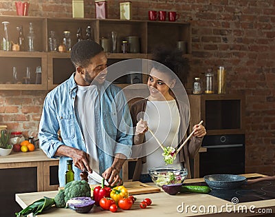 Loving afro american couple preparing green salad in kitchen Stock Photo