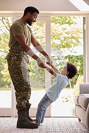 Loving Army Father In Uniform Home On Leave With Son Standing On Feet And Holding Hands Stock Photo