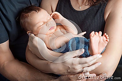 Loving baby sleeping in parents hands. Closeup picture. Happy mother and father and they slipping newborn baby Stock Photo