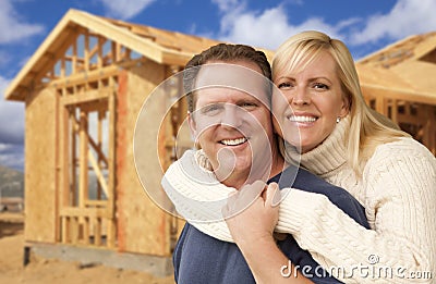 Loving Couple in Front of New Home Construction Framing Site Stock Photo