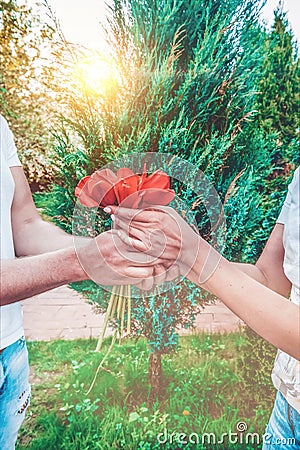 Loving couple holding a bouquet of tulips on a background of beautiful trees. A man gives his beloved flowers Stock Photo