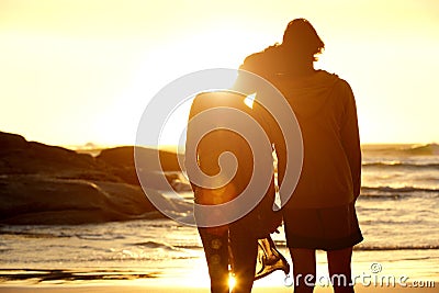 Loving couple holding hands at the beach watching the sunset Stock Photo