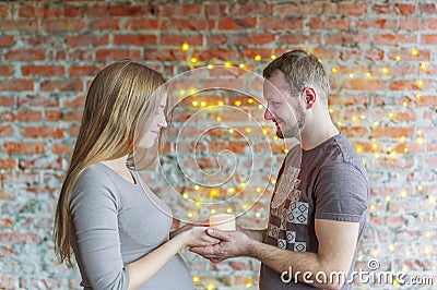 The loving couple holds the burning candle in hand. The woman is pregnant. Stock Photo