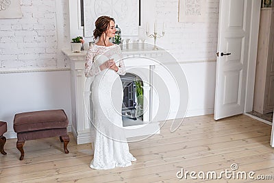 Loving couple of newlyweds with bouquit stand near fireplace Stock Photo
