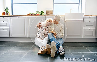 Loving couple sitting on kitchen floor Stock Photo