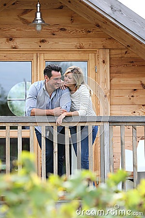 Loving couple standing on wooden house's terrace Stock Photo