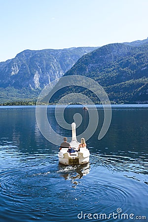 A loving couple swims in a boat in the form of a swan on a lake in the Austrian Hallstatt. Editorial Stock Photo
