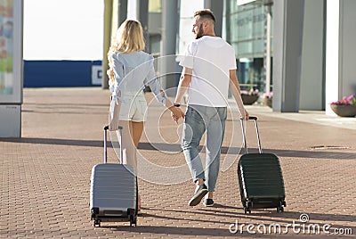 Loving couple walking to airport entrance with luggage Stock Photo