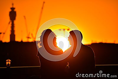 loving couple watching beautiful bright romantic sunset, sitting leaning against blue sport car. The fields around them. The youn Stock Photo