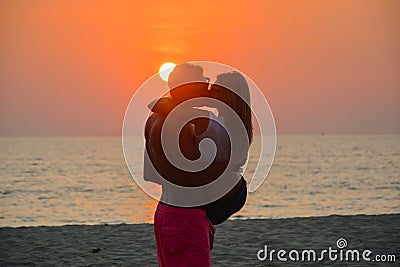 A loving couple watching the sunset on the beach Stock Photo