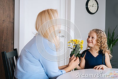 Loving daughter gives bouquet flowers to her mother. Girl gives a gift to her beloved mother. Stock Photo