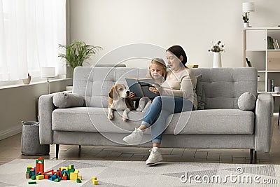 Loving dog owner grandma teaching little granddaughter to read book Stock Photo