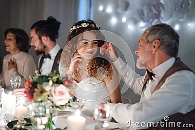 A loving father and beautiful bride sitting at the table on a wedding, talking. Stock Photo