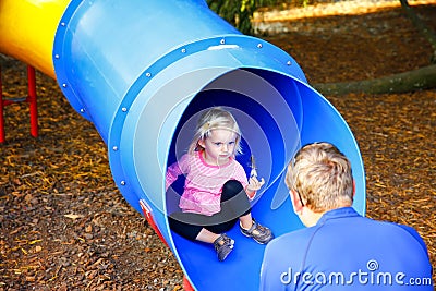 Loving father catching his little daughter at the slide. Stock Photo