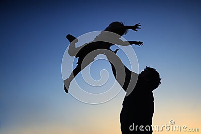 Loving father and his little son having fan together outdoors. Family as silhouette on sunset. Stock Photo