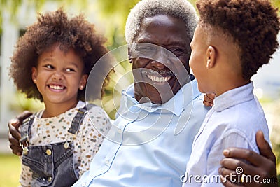 Loving Grandfather Talking With Grandchildren In Garden At Home Stock Photo