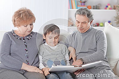 Loving grandparents with grandchild sitting on sofa Stock Photo