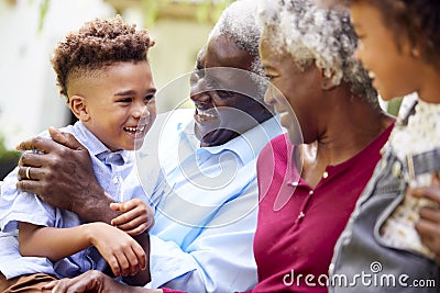 Loving Grandparents Talking With Grandchildren In Garden At Home Stock Photo