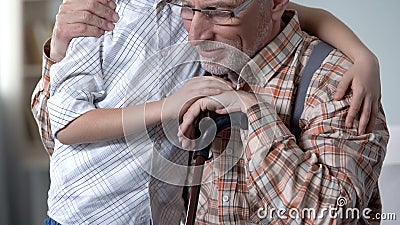 Loving grandson embracing grandfather, care and support for older generation Stock Photo