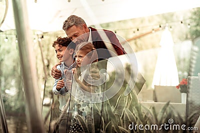 Loving grey-haired daddy hugging his cute lovely boy and girl Stock Photo