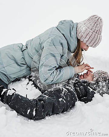 Loving guy and girl are lieing in the snow. Young happy couple walking in winter Stock Photo