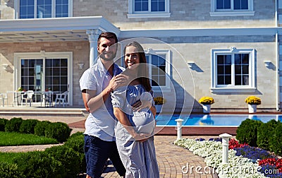 Loving husband and pregnant wife posing in front of new modern h Stock Photo