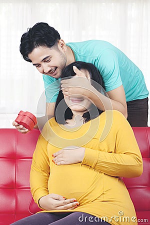 Loving husband surprises pregnant wife with gift Stock Photo