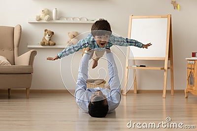 Loving Indian father lifting excited son pretending flying on floor Stock Photo