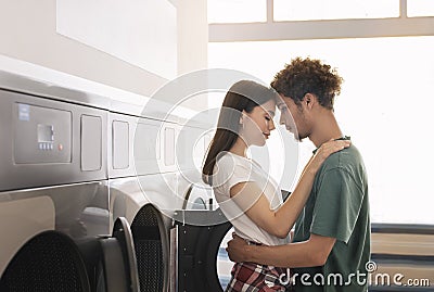 Loving Mixed Couple Hugging Standing Near Laundromat Washing Machines Indoor Stock Photo