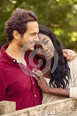 Loving Mixed Race Couple Leaning On Fence On Walk In Countryside Stock Photo