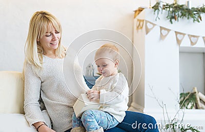 The loving mother and her little daughter sit at home on a sofa. Are happy together. Stock Photo