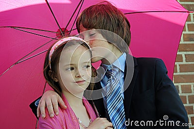 Loving siblings under pink umbrella Stock Photo