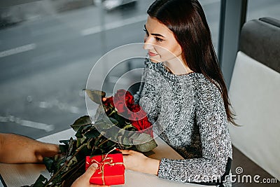 Loving young couple on date, man giving roses and gift to his gi Stock Photo