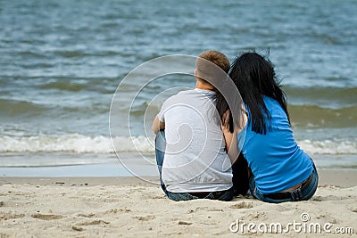 Loving young couple is sitting near the sea Stock Photo