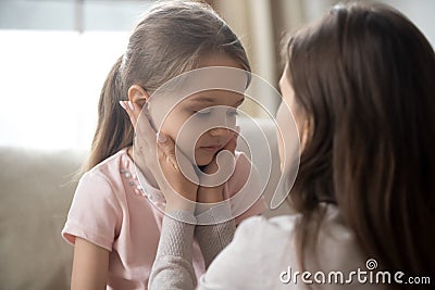 Loving young mother touching upset little daughter face, supporting Stock Photo