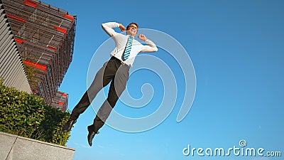 LOW ANGLE: Athletic businessman jumps high in the air after successful meeting. Stock Photo